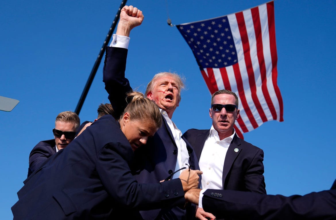 trump with his fist in the air, bleeding from his ear