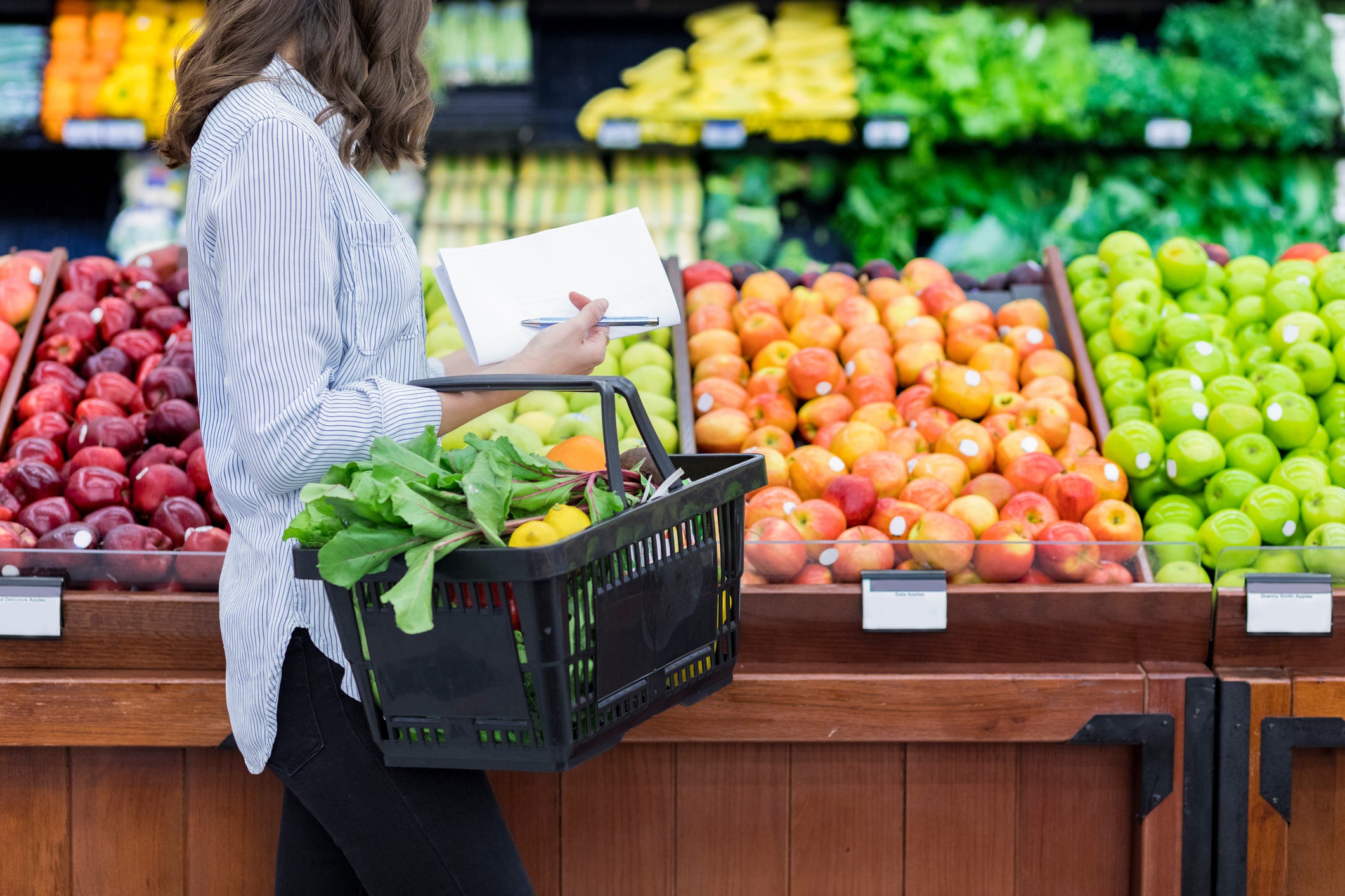 A photo shows a woman in a grocery store in the fruit aisle.