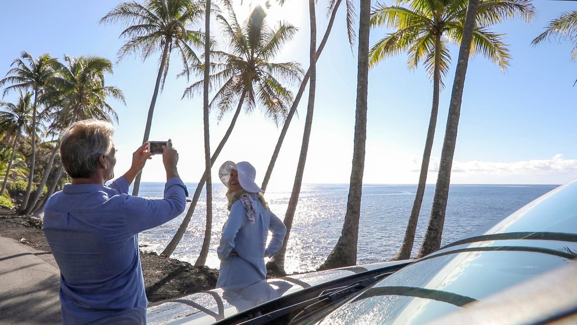 Man taking a photo of woman near the ocean