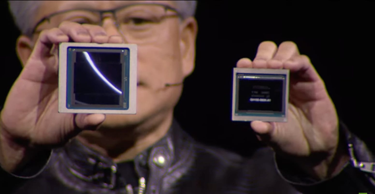 Huang holds up two chips while speaking onstage at the GTC conference.