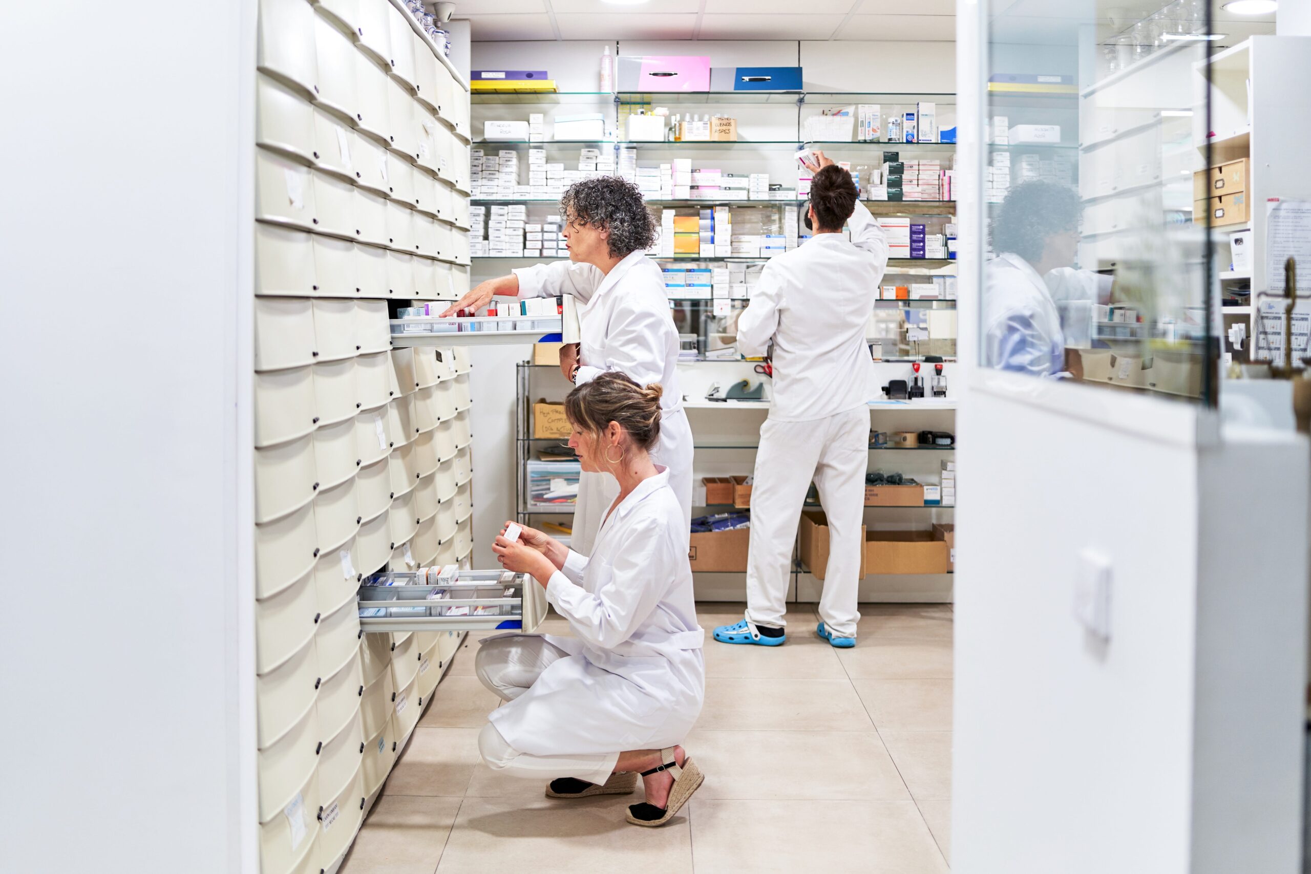 three workers in a pharmacy setting