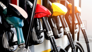 A photo of a row of gasoline pump handles at a pump with the sun shining on them. Gas prices dropping.