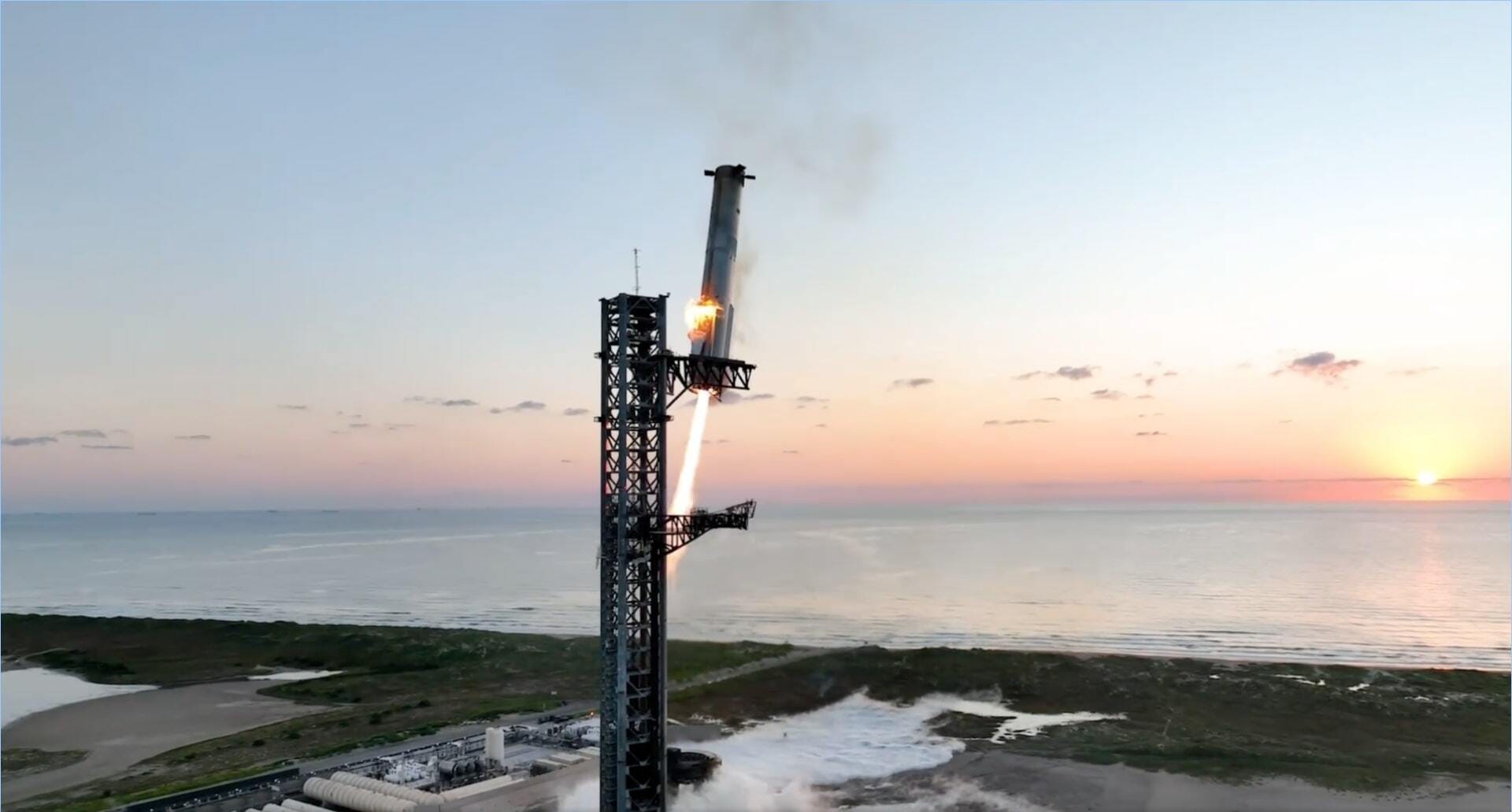 SpaceX's Super Heavy booster as it returned to its launch site, with the sun rising in the background.